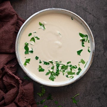 white bowl with tahini sauce and parsley