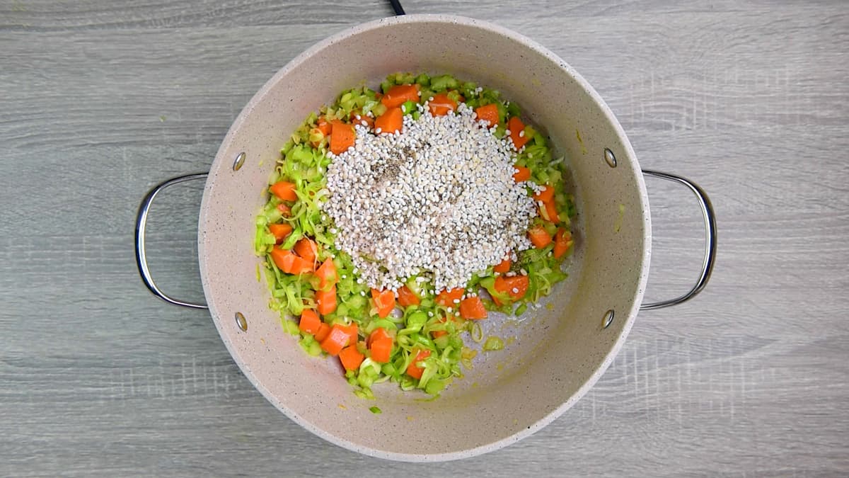 adding pearl barley, salt and pepper to vegetables in pot.
