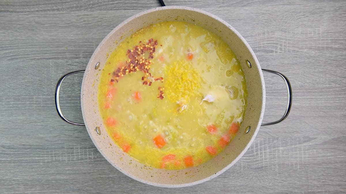 adding lemon and red pepper flakes to pot of chicken barley soup.