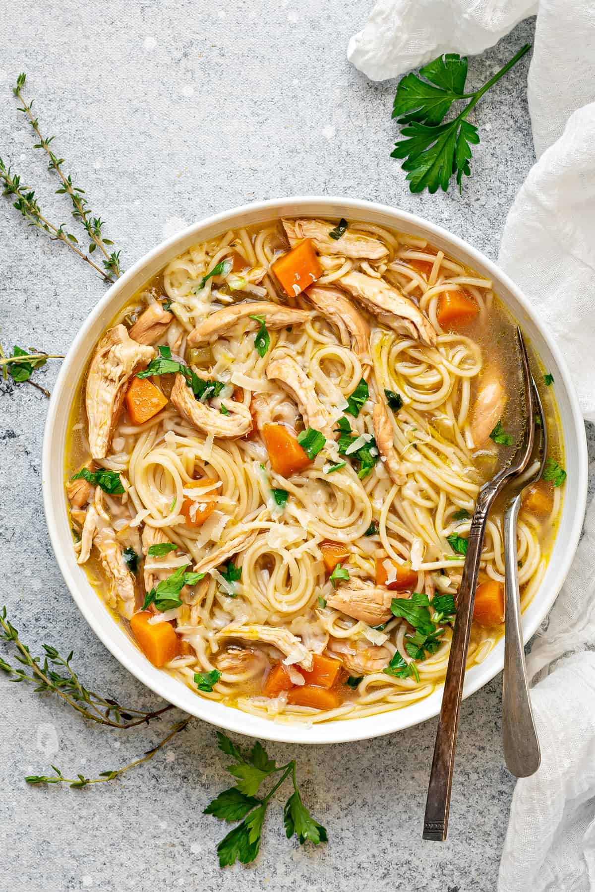 one bowl of chicken noodle soup with a fork and spoon 