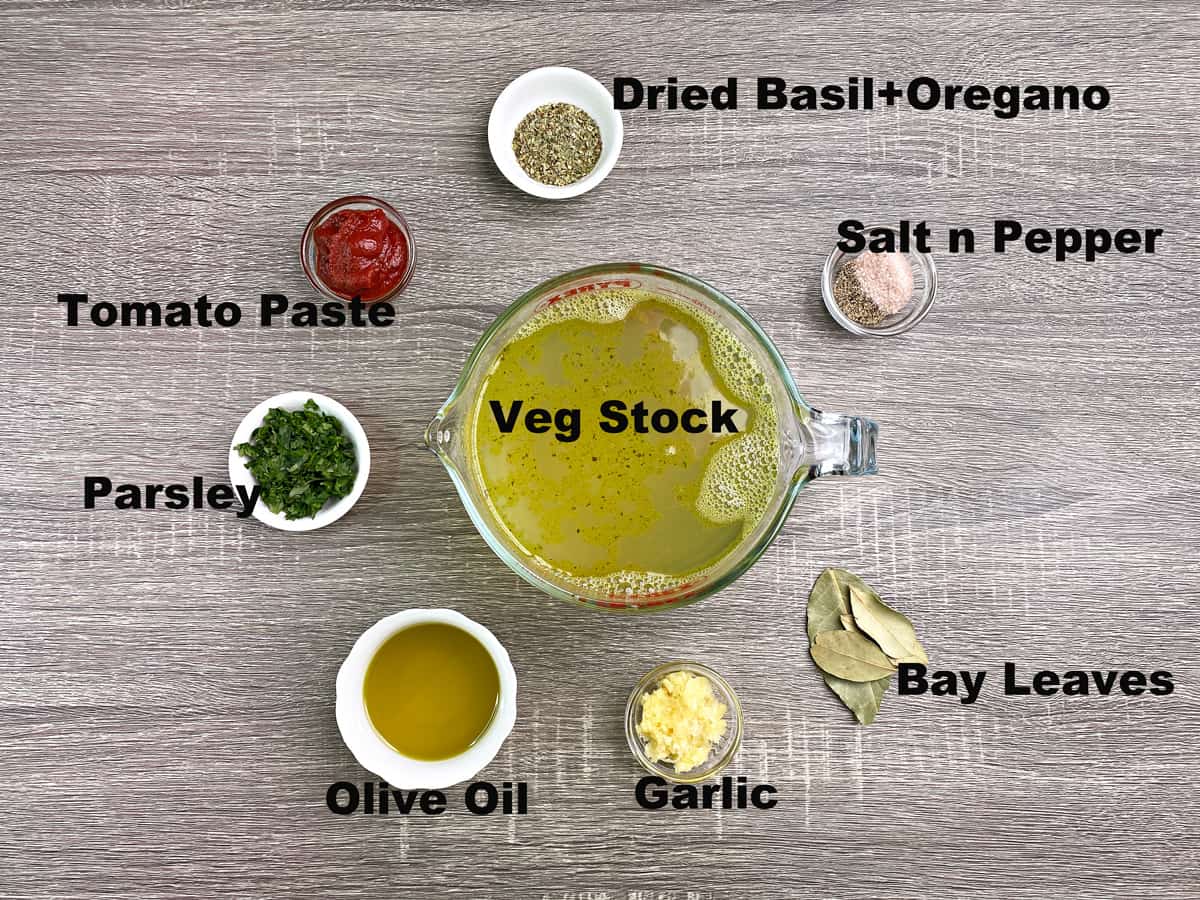 veg stock, basil, oregano, salt, pepper, bay leaves, garlic, olive oil, parsley, tomato paste in bowls