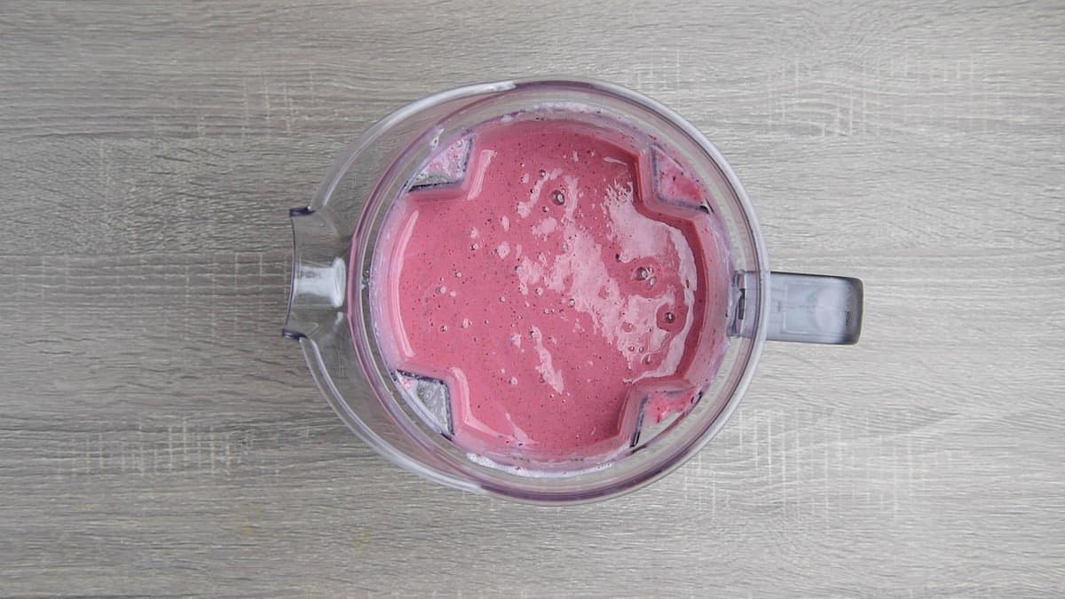 blender jar with pink mixed berry smoothie
