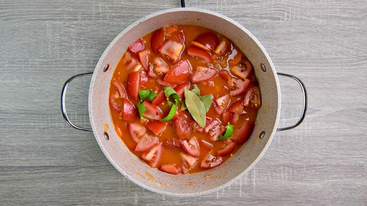 broth, fresh basil, red pepper flakes, bay leaves added to tomatoes in pot.