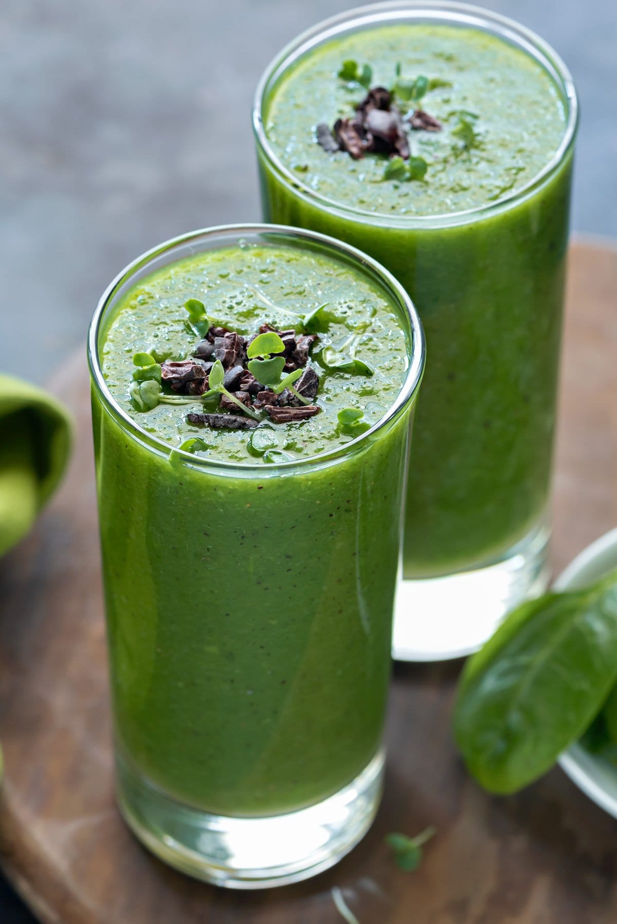two glasses of green detox smoothie with cacao nibs and microgreens