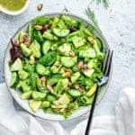 one bowl of mixed green salad with avocado, apple, dill, and dressing