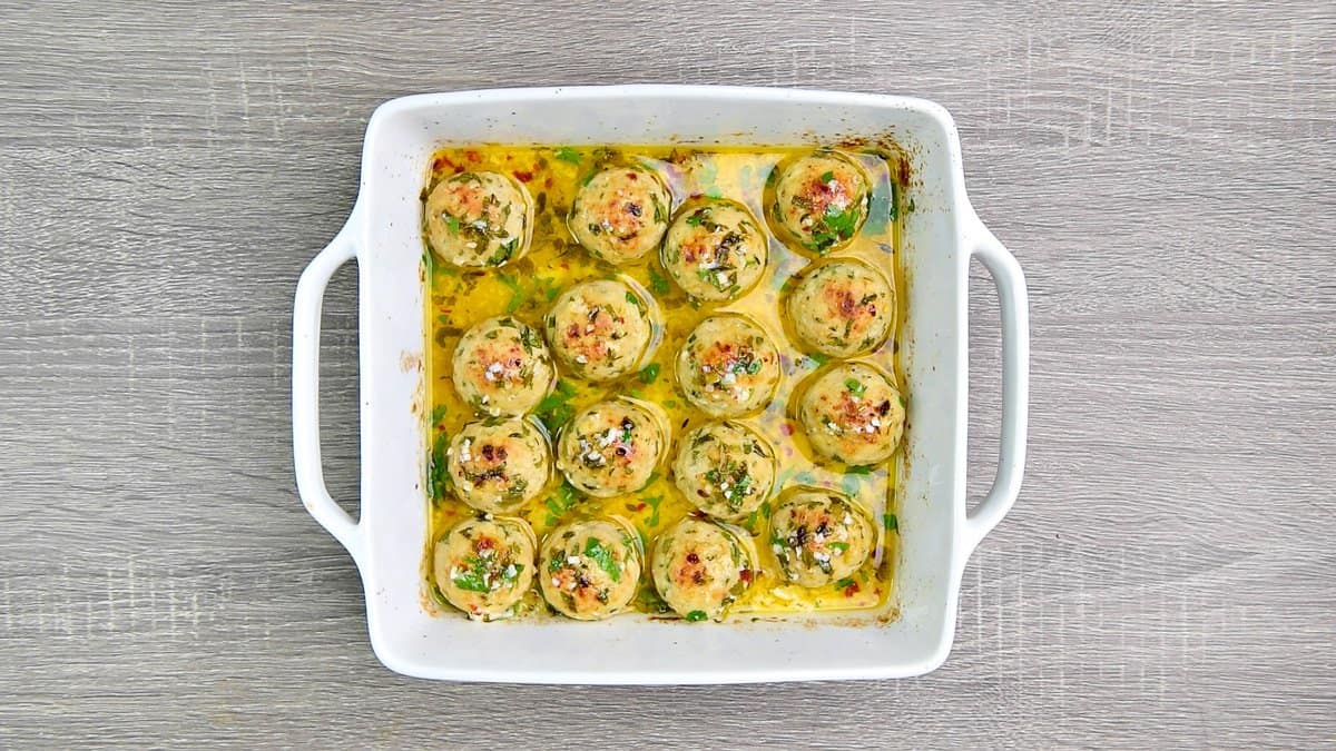 Fully baked turkey meatballs in lemon butter sauce in a casserole dish ready to be served. 