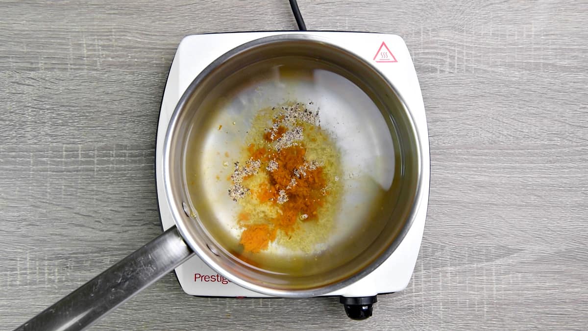 Filtered water, grated fresh turmeric, fresh ginger and black pepper added to the saucepan.