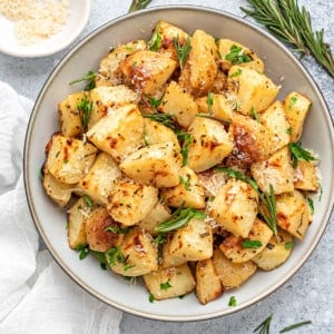 Rosemary Roasted Potatoes on a round plate with parmesan cheese in a small bowl.