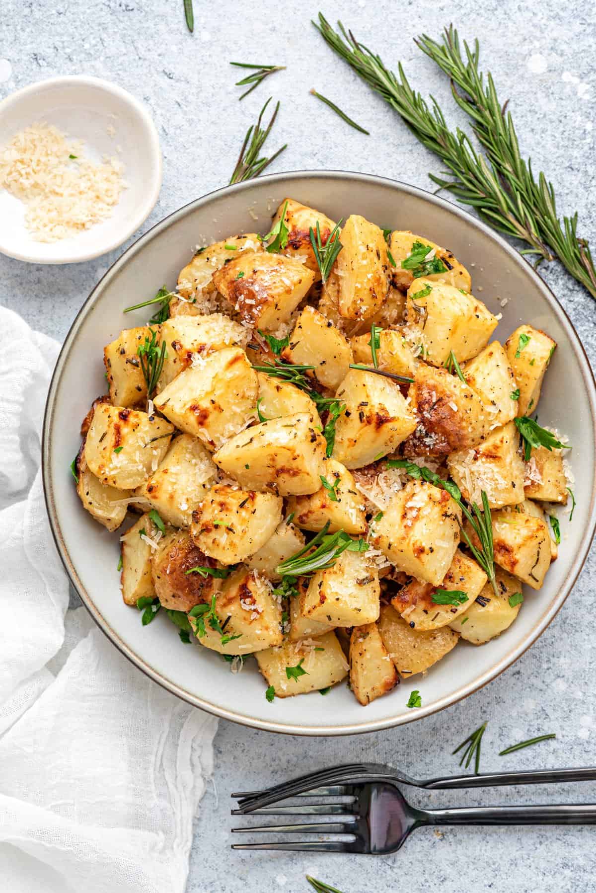 Rosemary Roasted potatoes on a round plate with parmesan cheese in a small bowl.