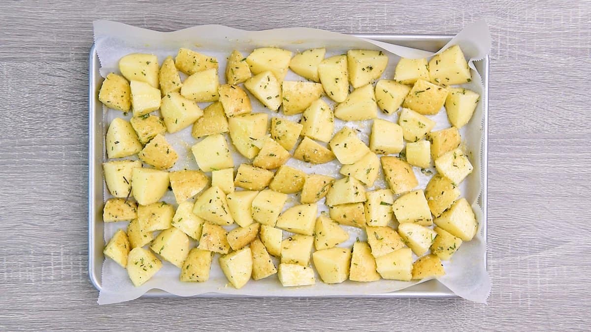 Potatoes are laid out on a pan lined with parchment paper.