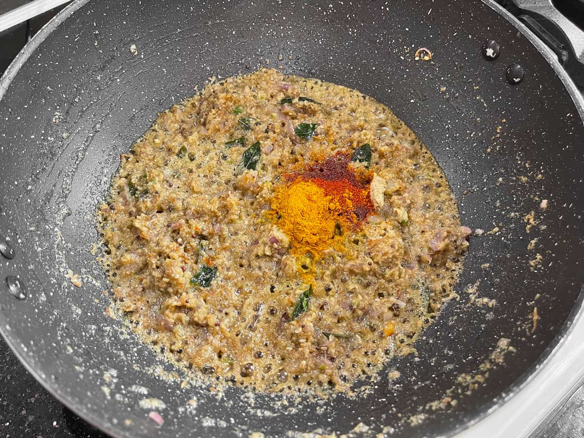 Turmeric powder and red chili powder added to the sautéed gravy base in the pan.