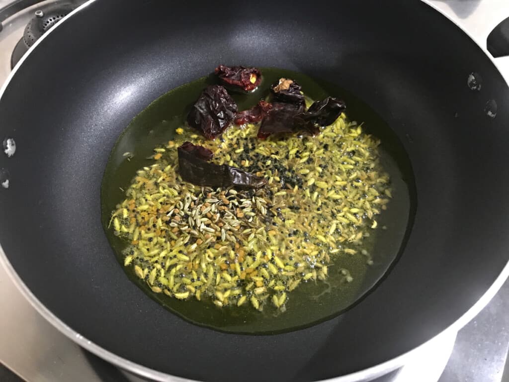 fenugreek, fennel, mustard, nigella, cumin seeds and dried red chillies added in hot oil in kadai.