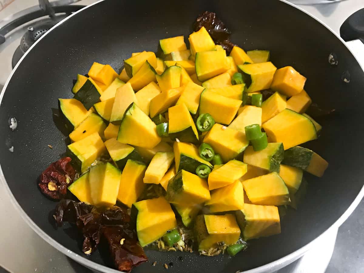cubed pumpkin and chopped green chillies added to the oil in kadai.
