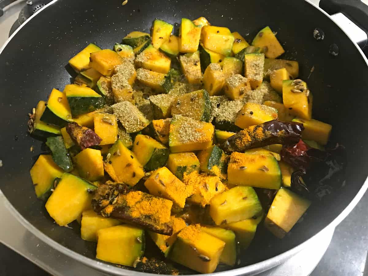 coriander powder and turmeric powder added to sautéed pumpkin in kadai.