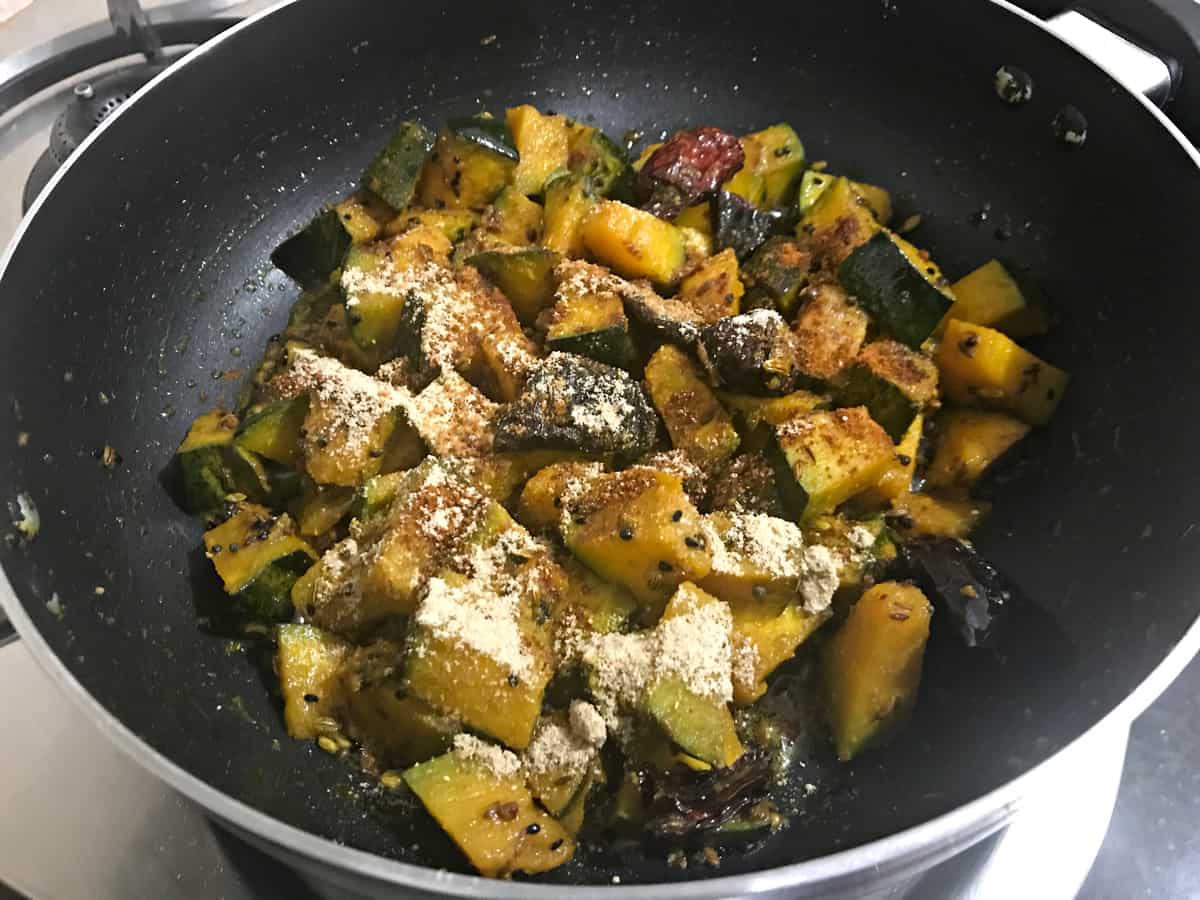 Dry mango powder and garam masala powder added to the pumpkin sabzi cooking in kadai.