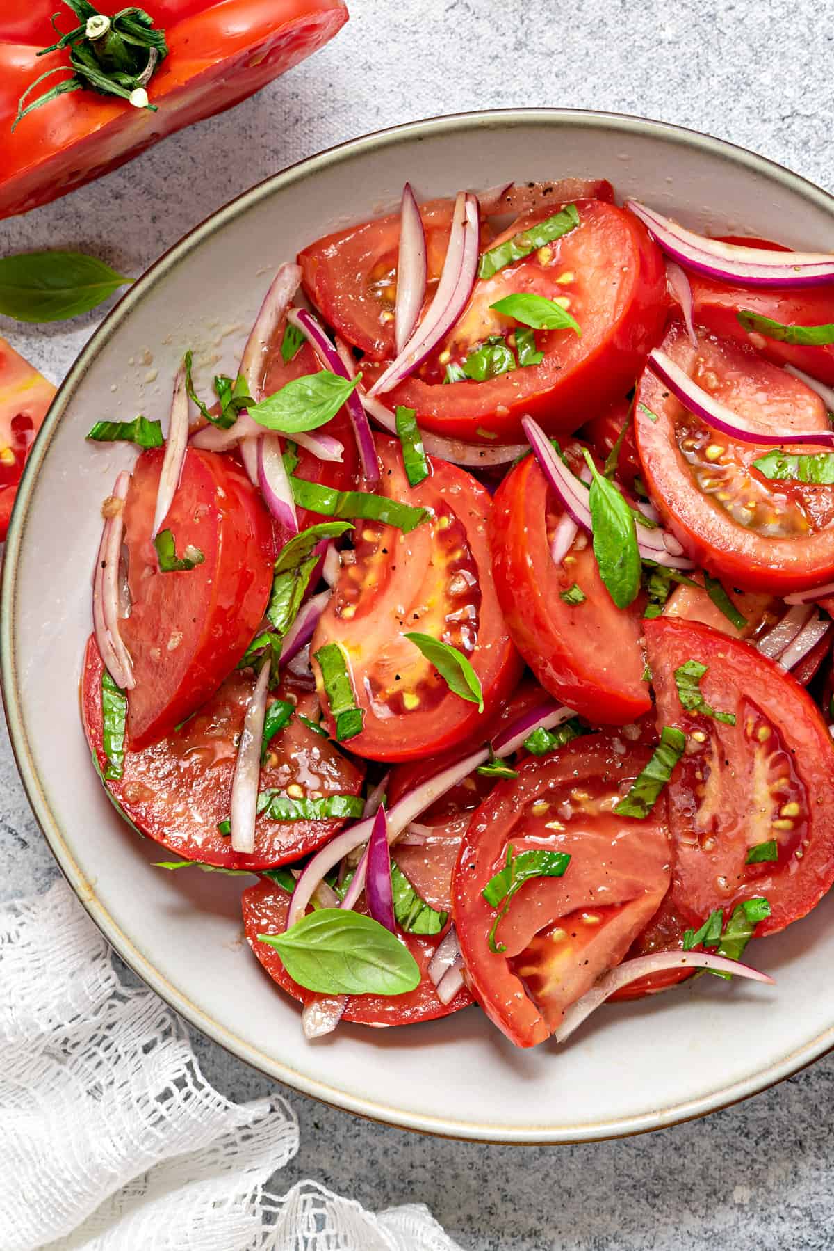 close-up shot of tomato salad with basil placed in grey earthenware.