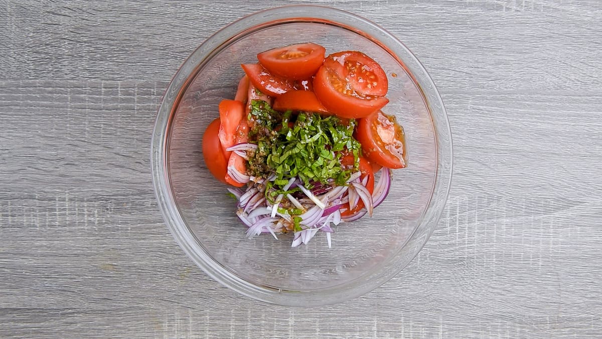 sliced tomatoes, red onion, basil ribbons and prepared balsamic dressing added in large bowl for tossing.
