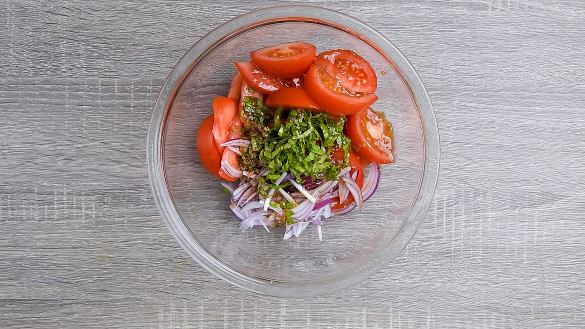 sliced tomatoes, red onion, basil ribbons and prepared balsamic dressing added in large bowl for tossing.