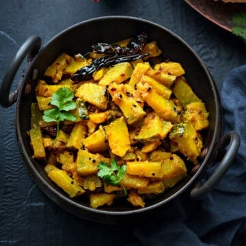 Kaddu ki sabji aka pumpkin sabzi garnished with cilantro and served in a black kadai.