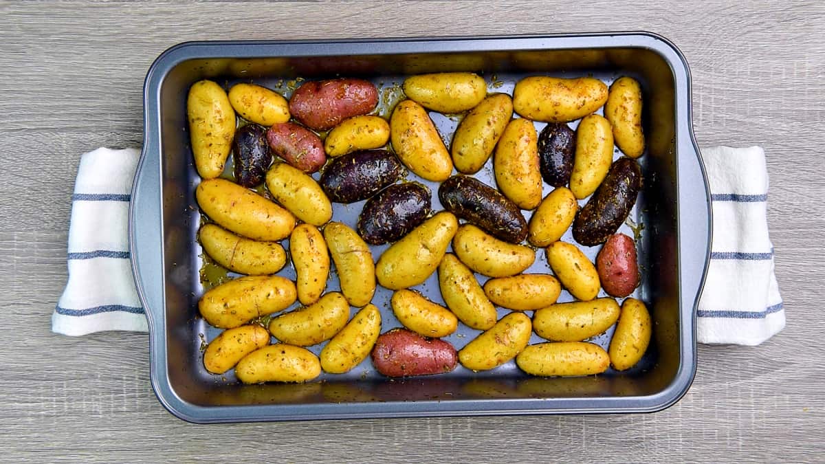 Potatoes cut side down in a roasting pan.