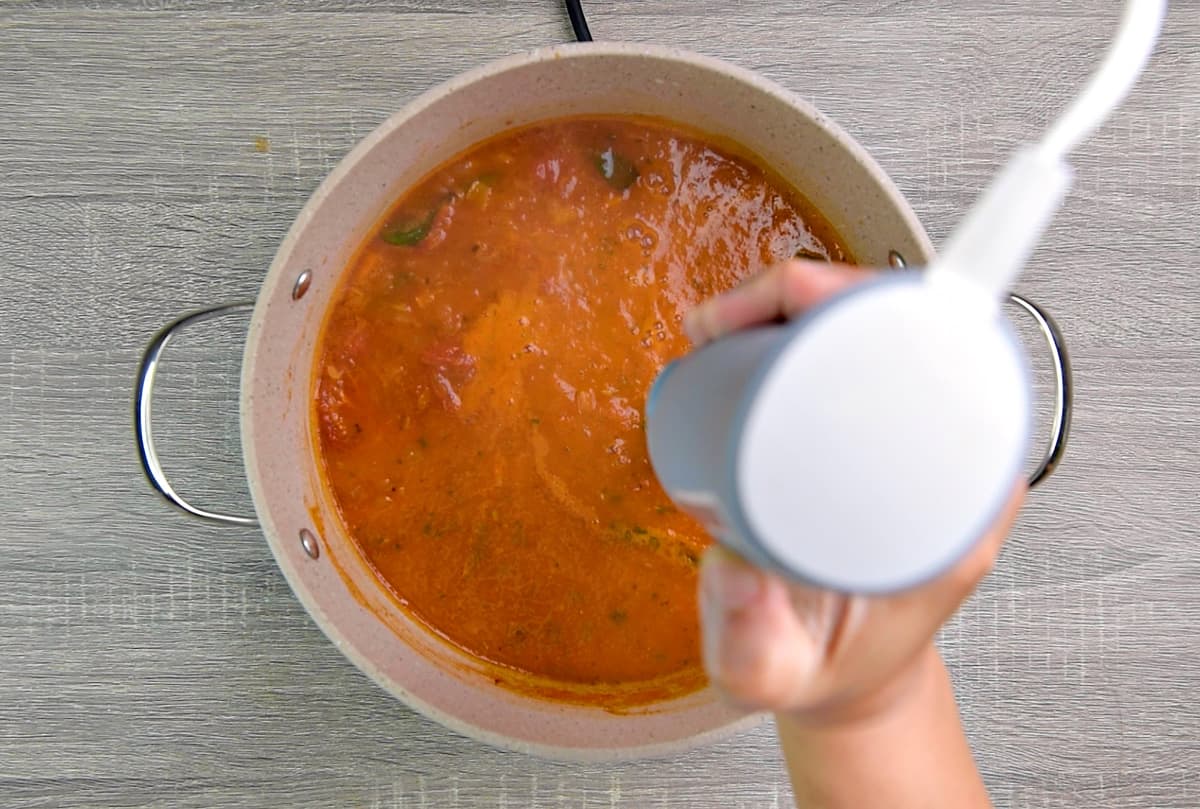 Using an immersion blender to blend the soup in pot.
