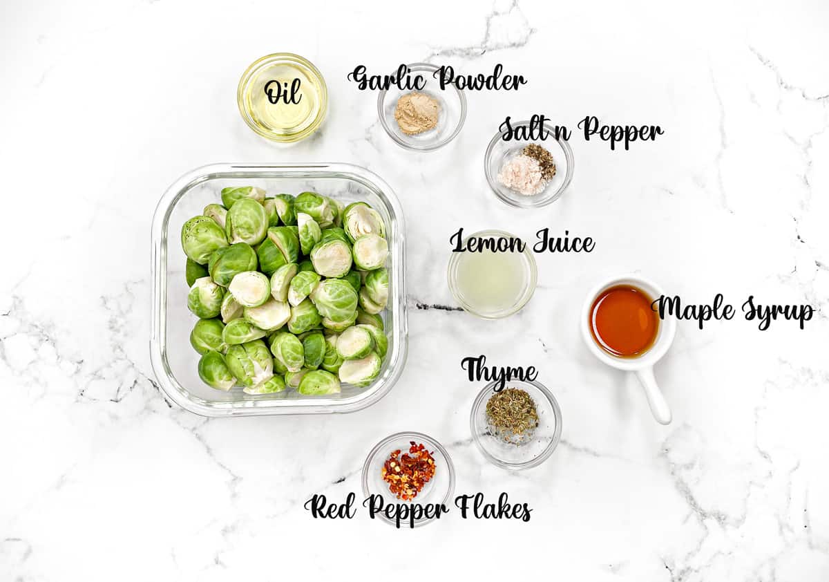 Ingredients in individual glass bowls: sprouts, thyme, maple syrup, lemon juice, garlic powder, seasonings and oil.