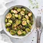 Top down close up of crispy air fryer brussel sprouts in white ceramic bowl.
