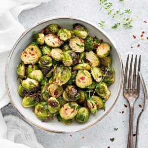 Top down close up of crispy air fryer brussel sprouts in white ceramic bowl.