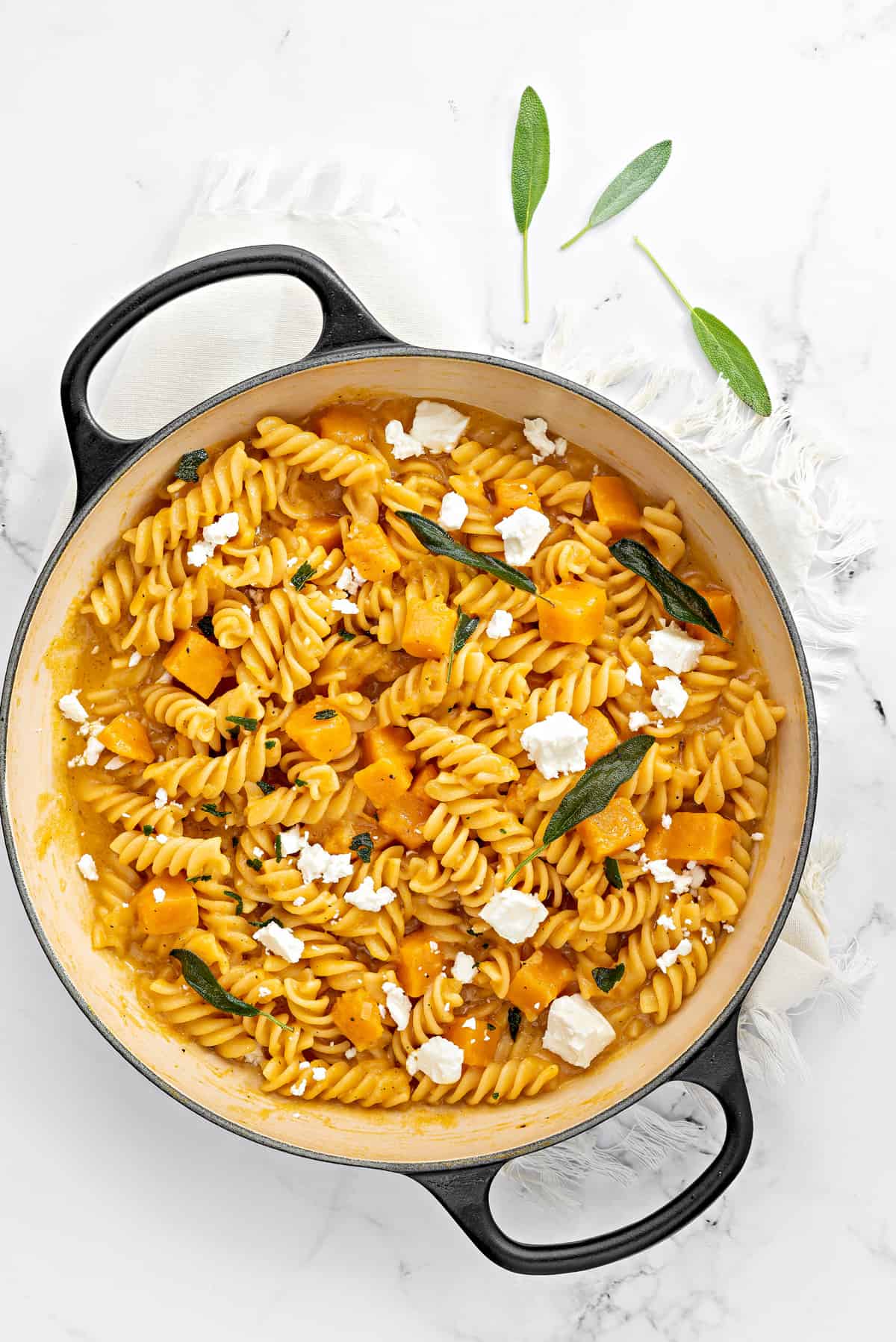 Top down shot of one pot pasta with butternut squash sauce sprinkled with crumbled feta cheese.