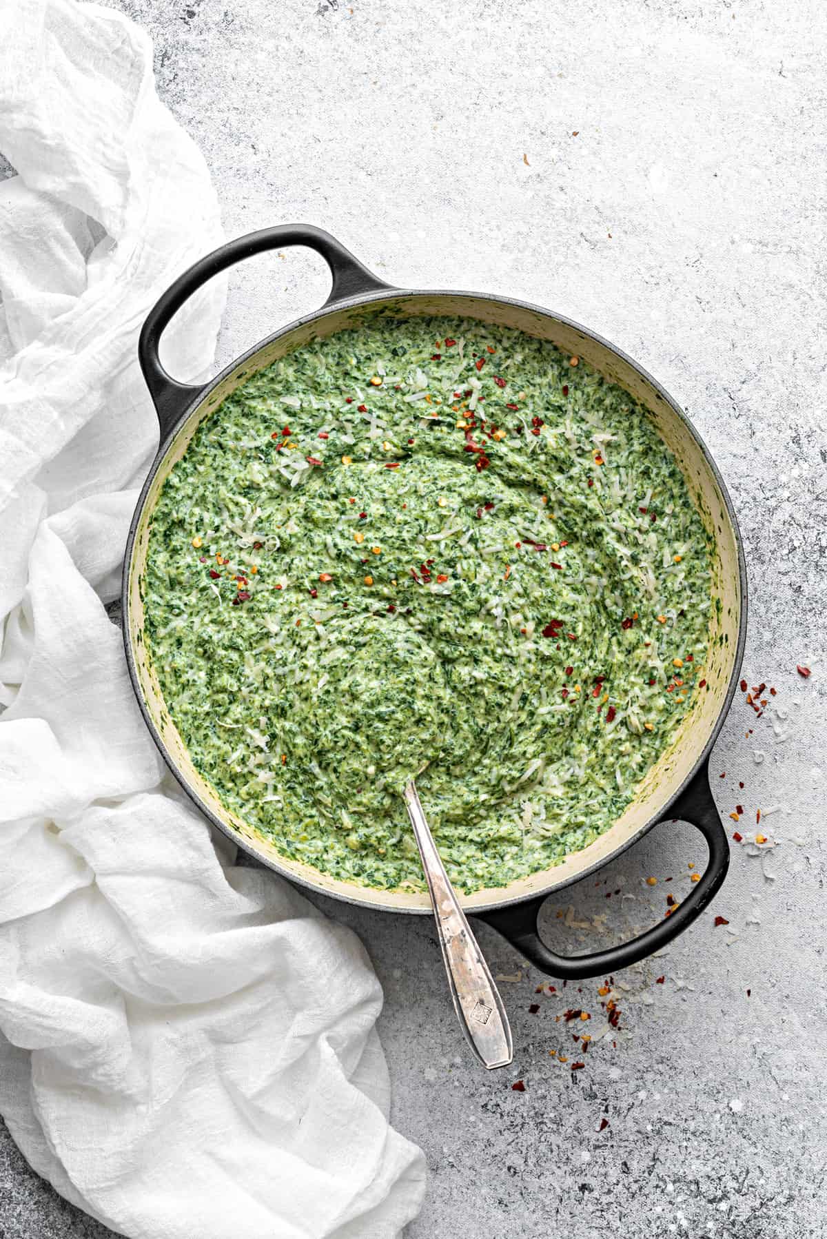 Final shot of creamed spinach recipe, with dish served in a large pot with metal spoon.