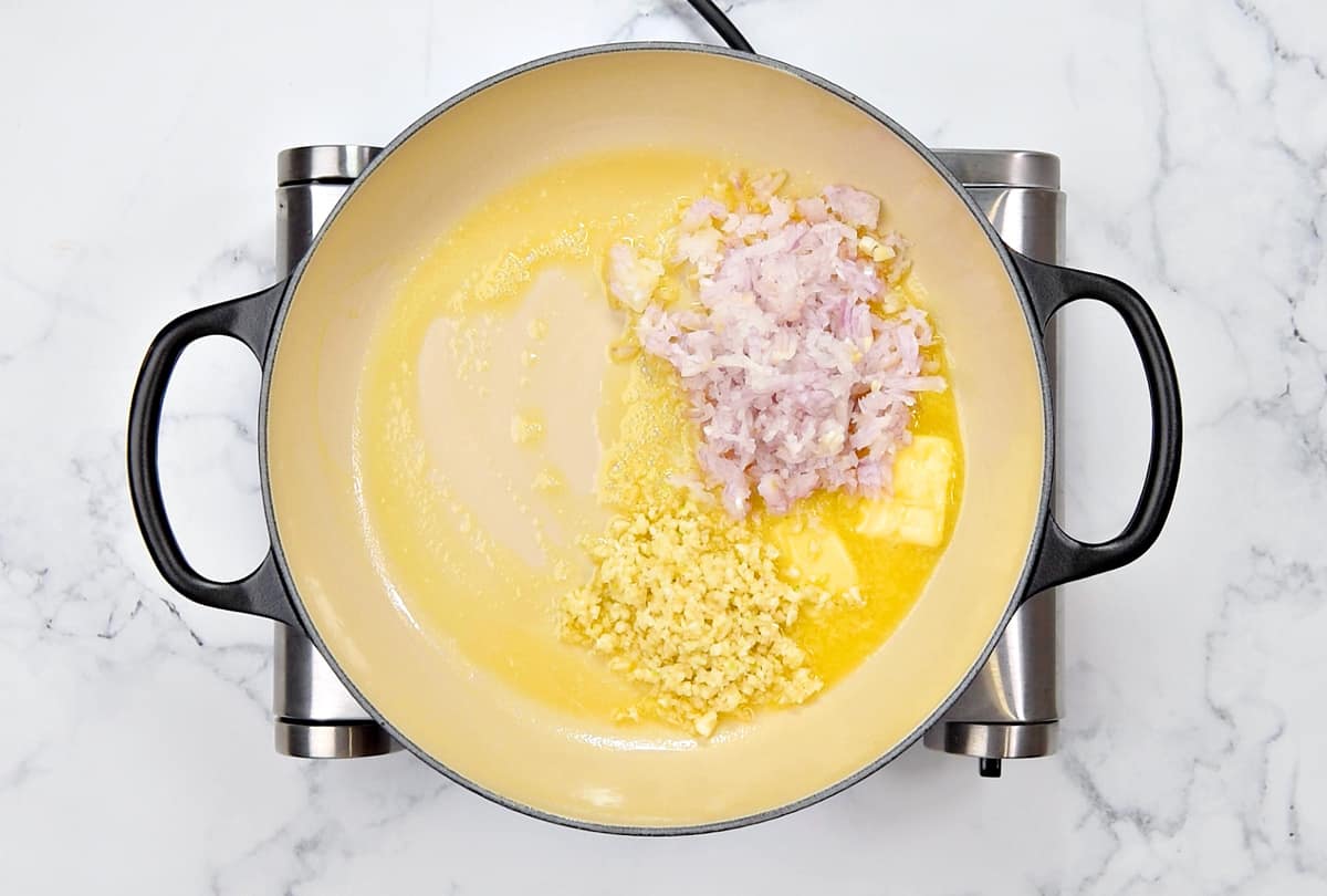 Sauteeing onion and garlic with butter in a large cooking pan.