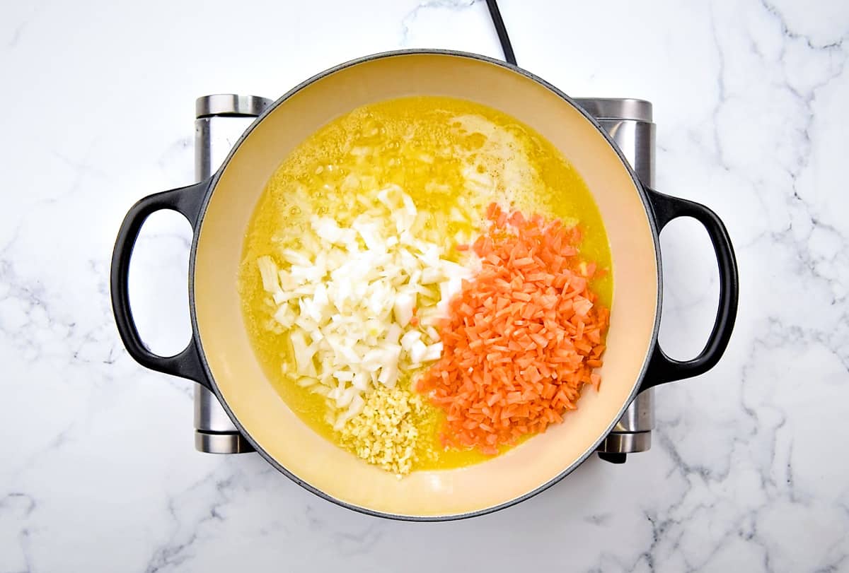 Chopped onion, carrot, and garlic in butter and olive oil in cooking pot.