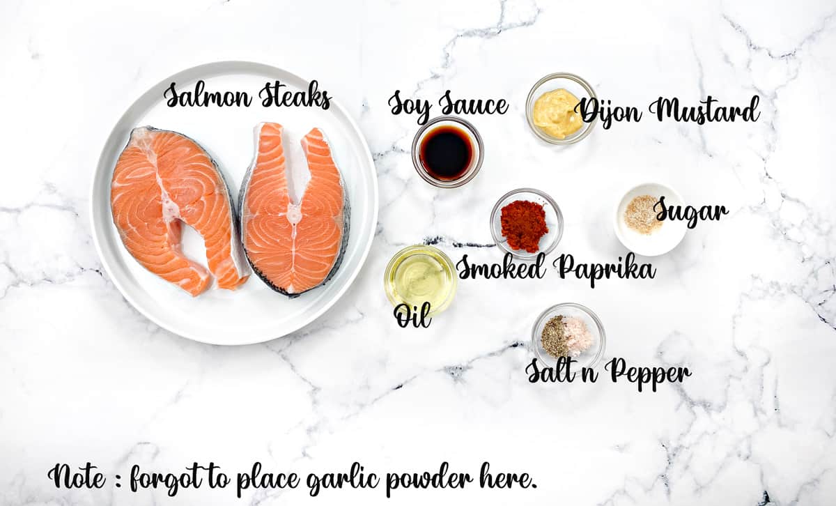 Ingredients to air fry salmon steak placed in individual bowls and kept on a white table.