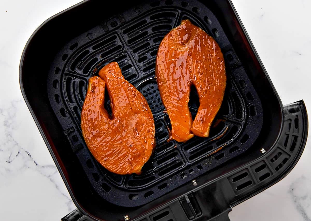 Pieces of marinated fish in air fryer basket.