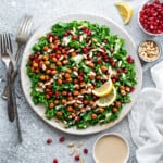 Overhead shot of vegan, gluten-free kale salad on a plate with ramekin of tahini sauce on the side.