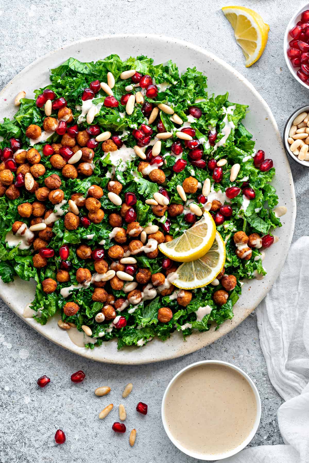 Large plate of kale salad main view with ramekin of tahini sauce.