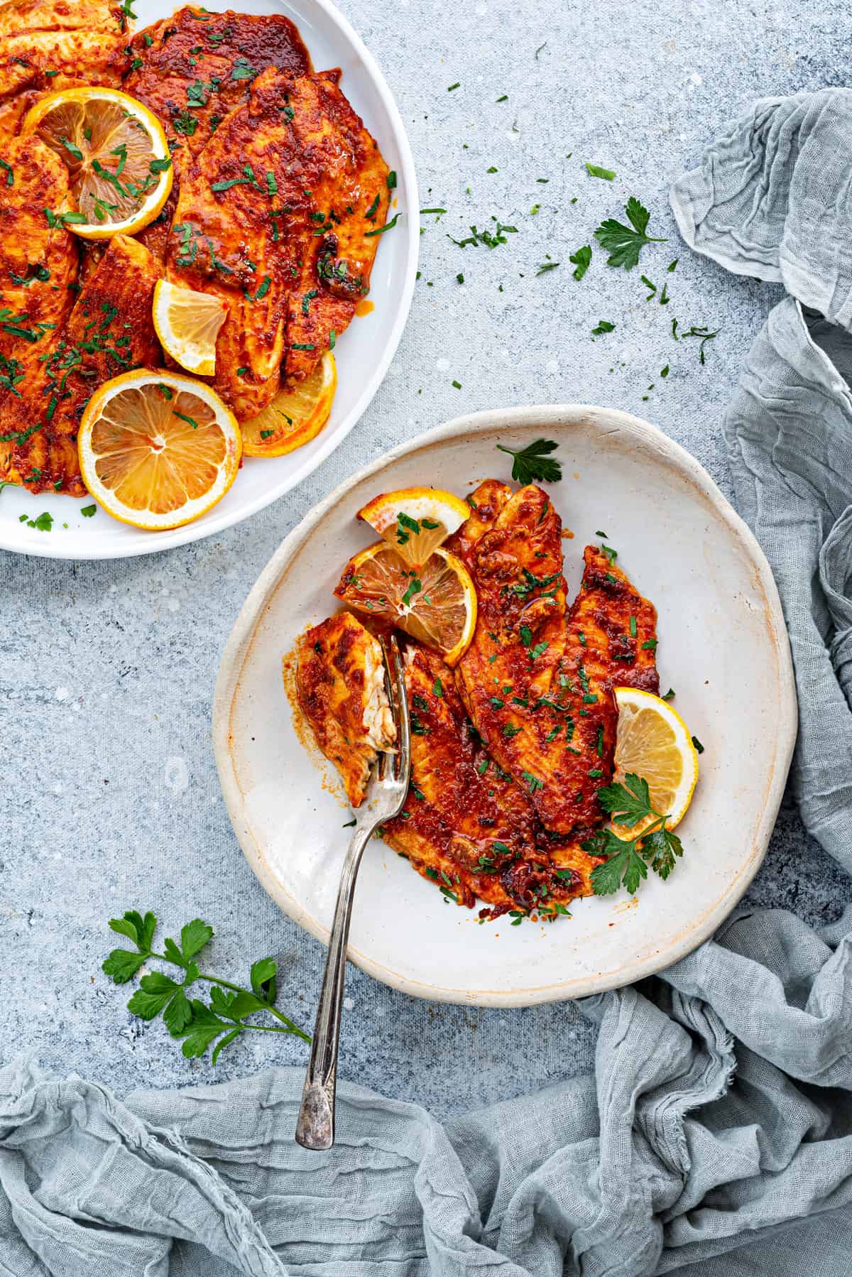 Baked tilapia fillets on a white dish with fork.