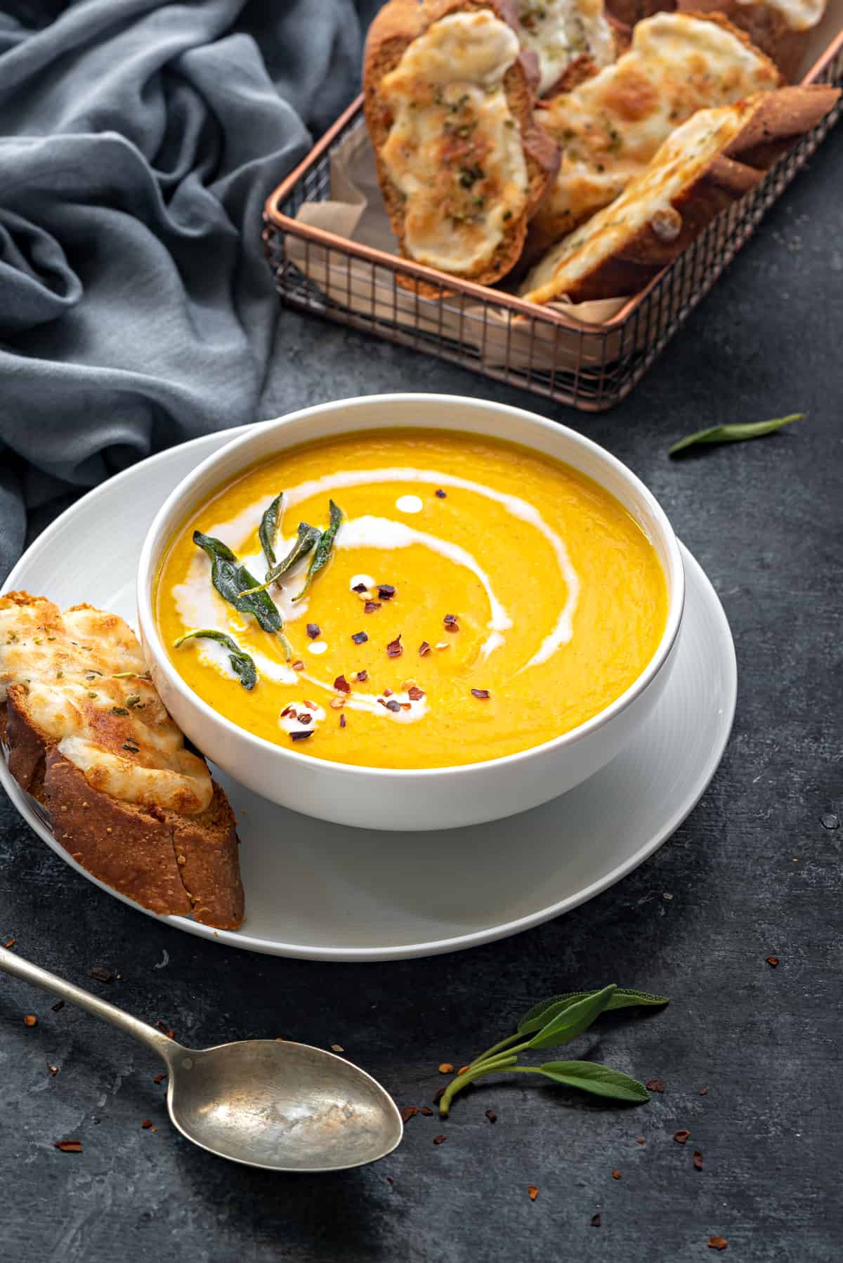 Roasted pumpkin coconut soup served in white bowl with cheese toast on side. 