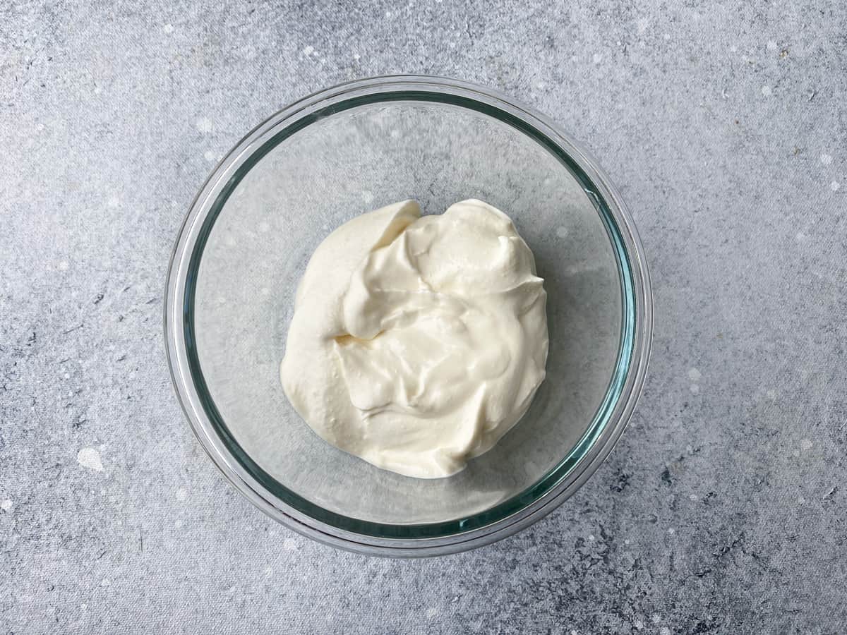 Creamy lemon dill sauce in a mixing bowl with a whisk.