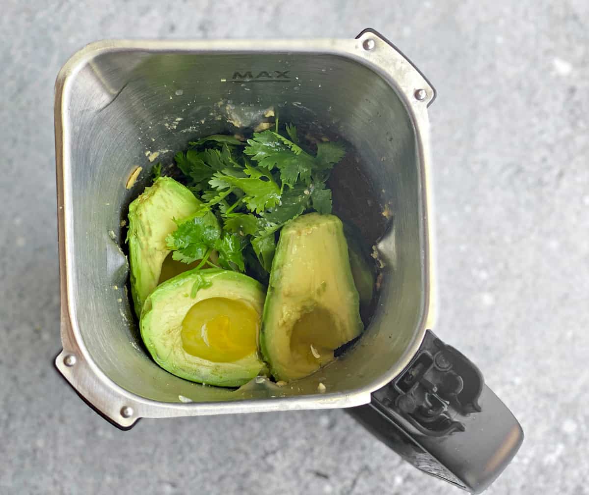 Avocado halves and fresh cilantro added to the blender.