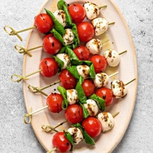 Large oval plate with 6 Caprese skewers drizzled with balsamic reduction.