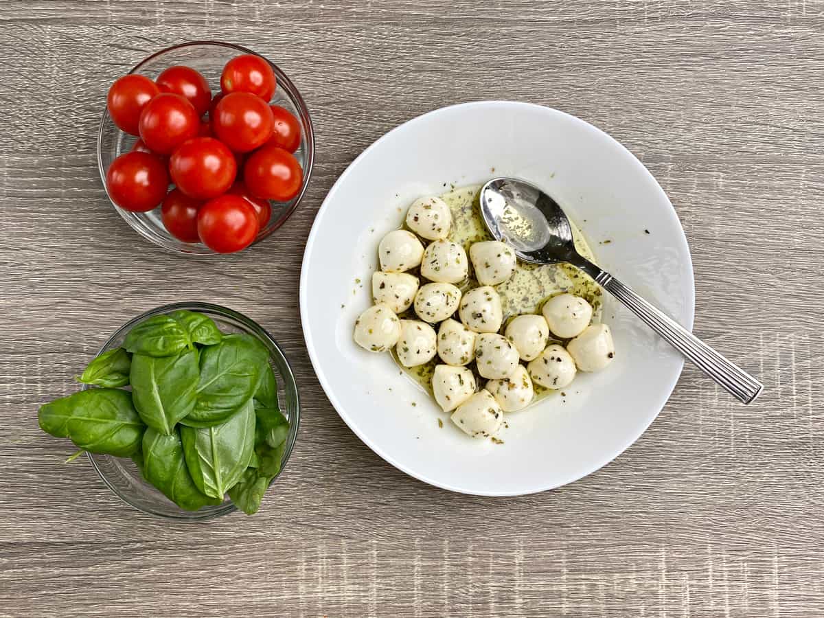 Marinating mozzarella cheese balls in oil with seasoning.