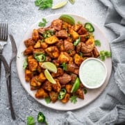 White circle plate loaded with crisp Mexican potatoes, slices of jalapeno and wedges of lime.