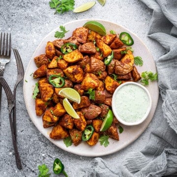 White circle plate loaded with crisp Mexican potatoes, slices of jalapeno and wedges of lime.