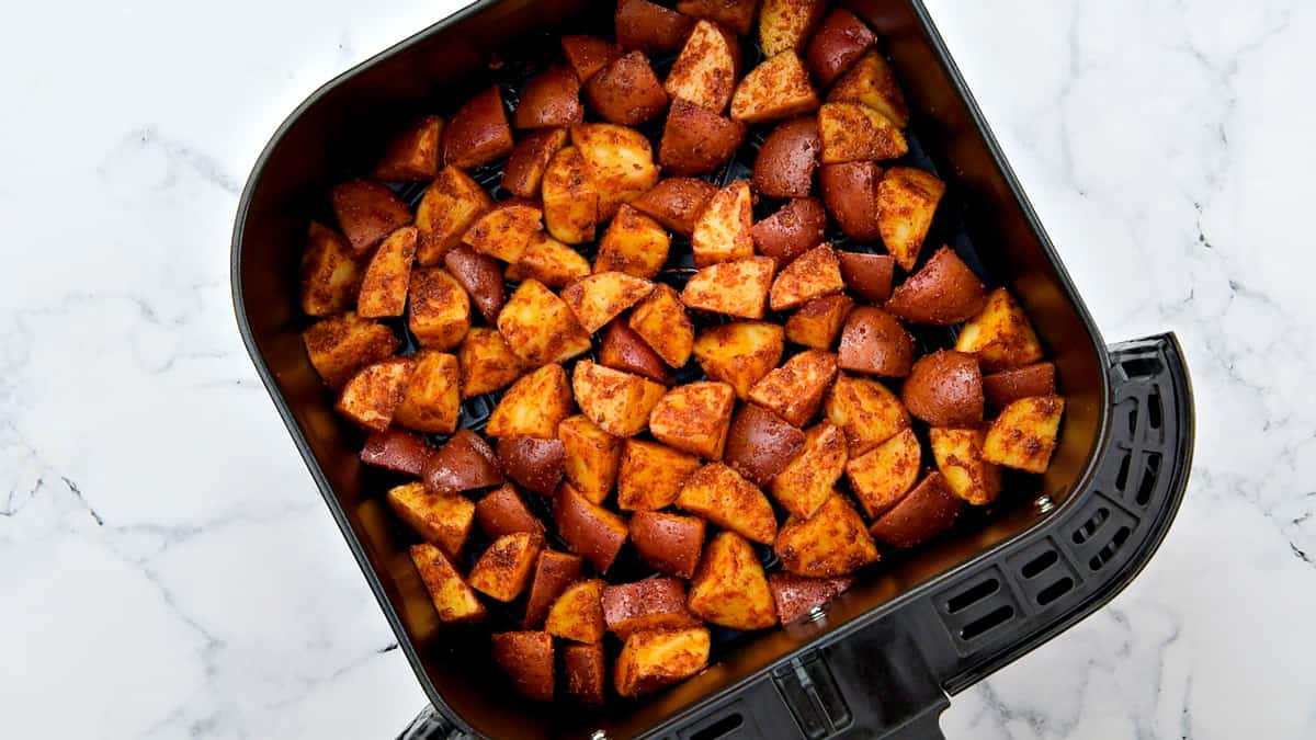 Seasoned Mexican potato cubes in an air fryer basket.