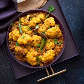 Close-up of Achari Gobi sabzi served in purple platter.