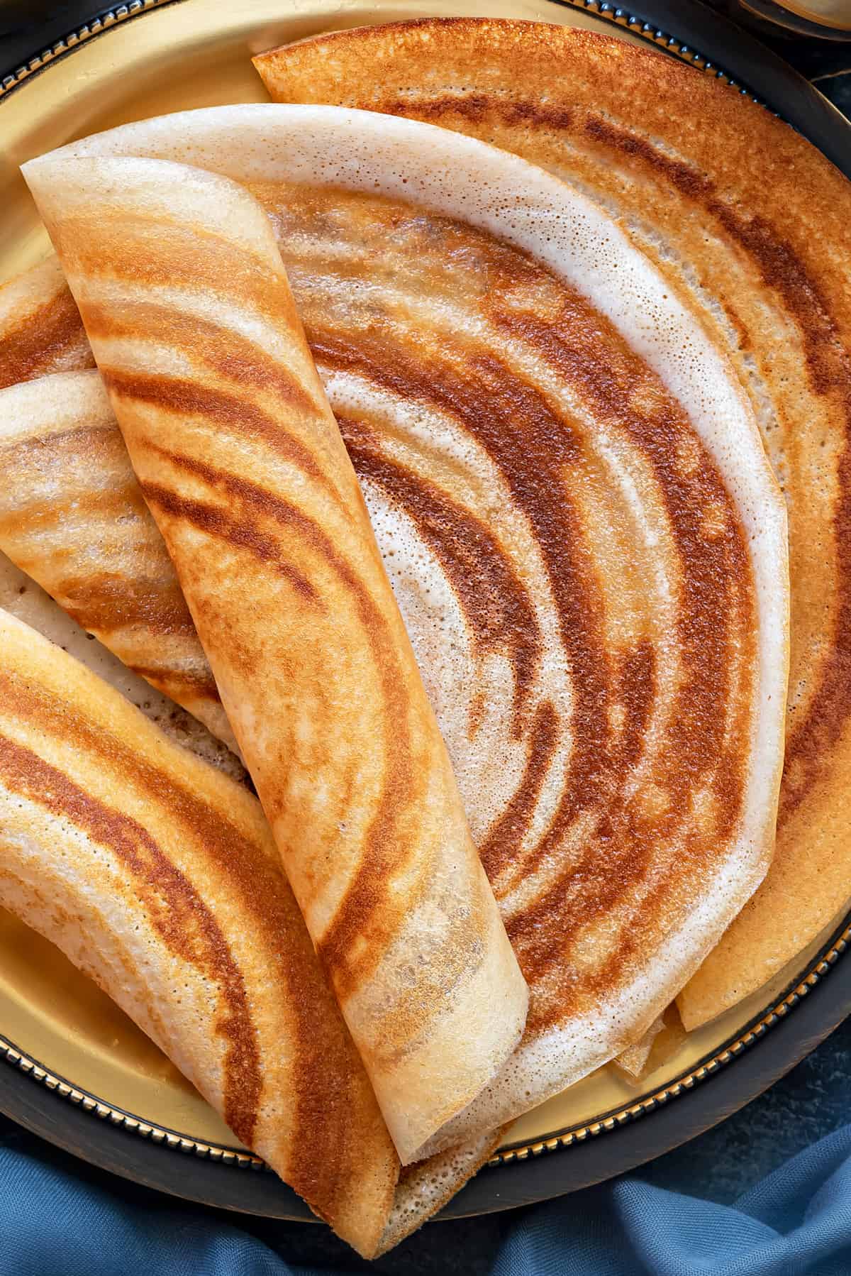 Close-up of south Indian plain dosa on brass plate.