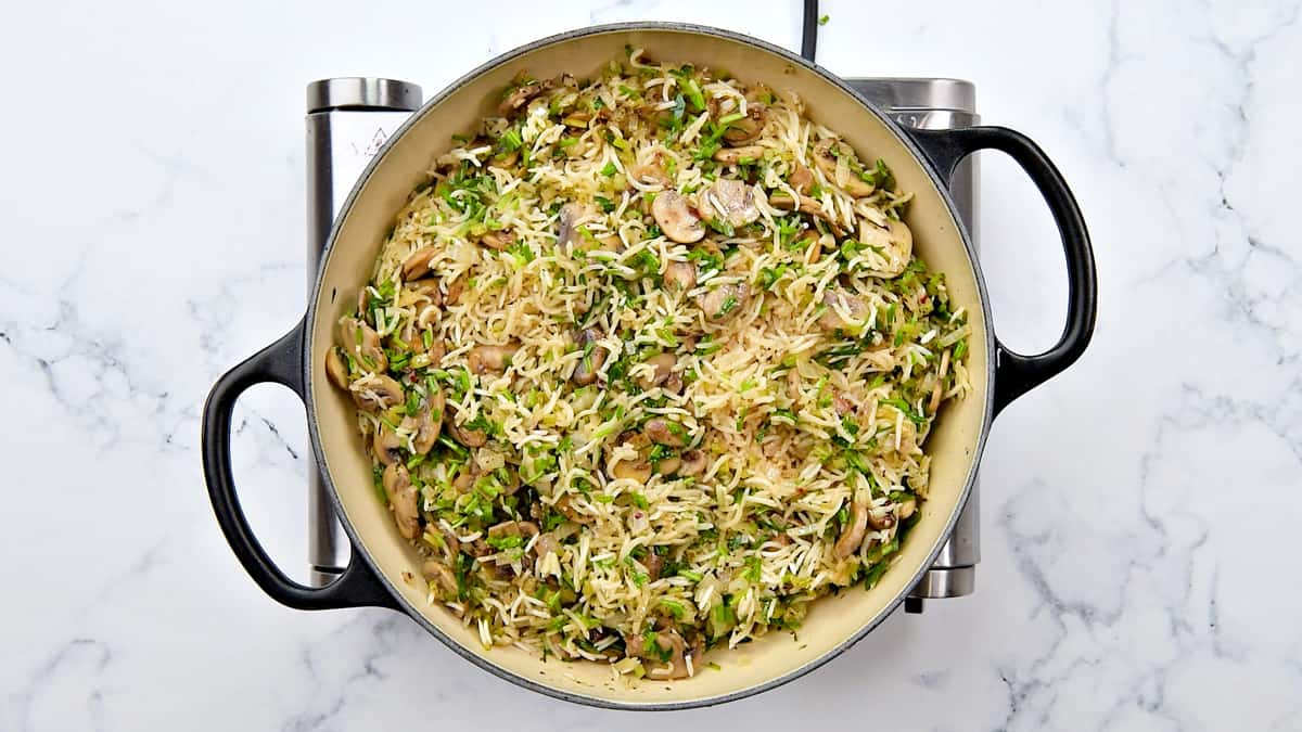 Fresh herbs stirred into the pot with mushrooms and rice.