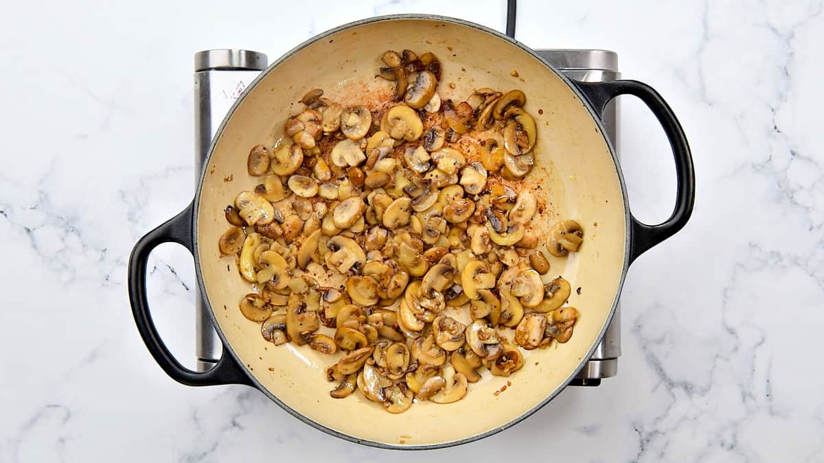 Sauteeing browned mushrooms in a pot.