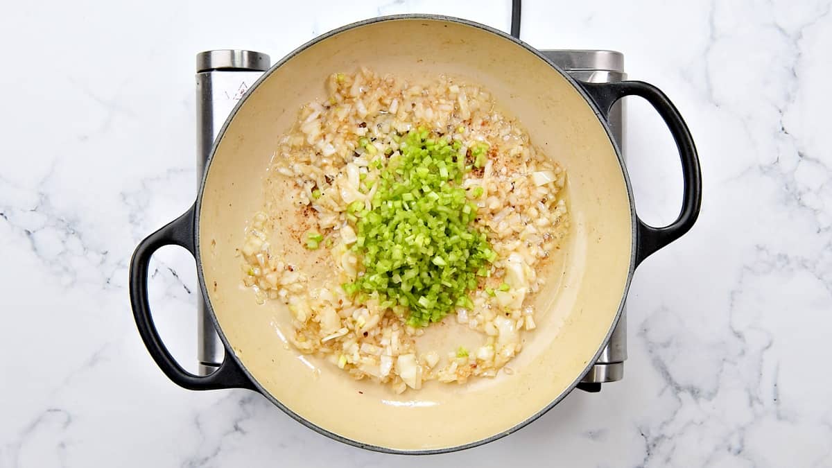 Celery and onion cooking together in a pot.